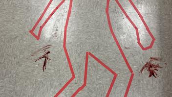an outline of a body in tape with "blood splatter" around it