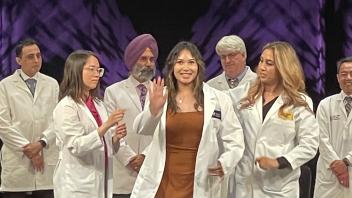 Monneca Rim poses on stage after receiving her white coat.