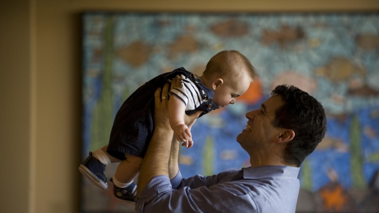 man lifting baby to look at his face