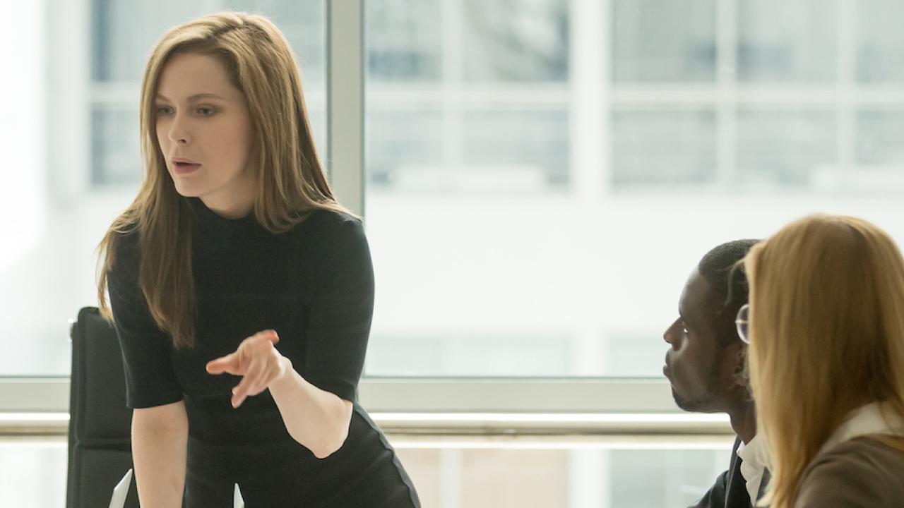 woman standing and speaking to colleagues in a conference room