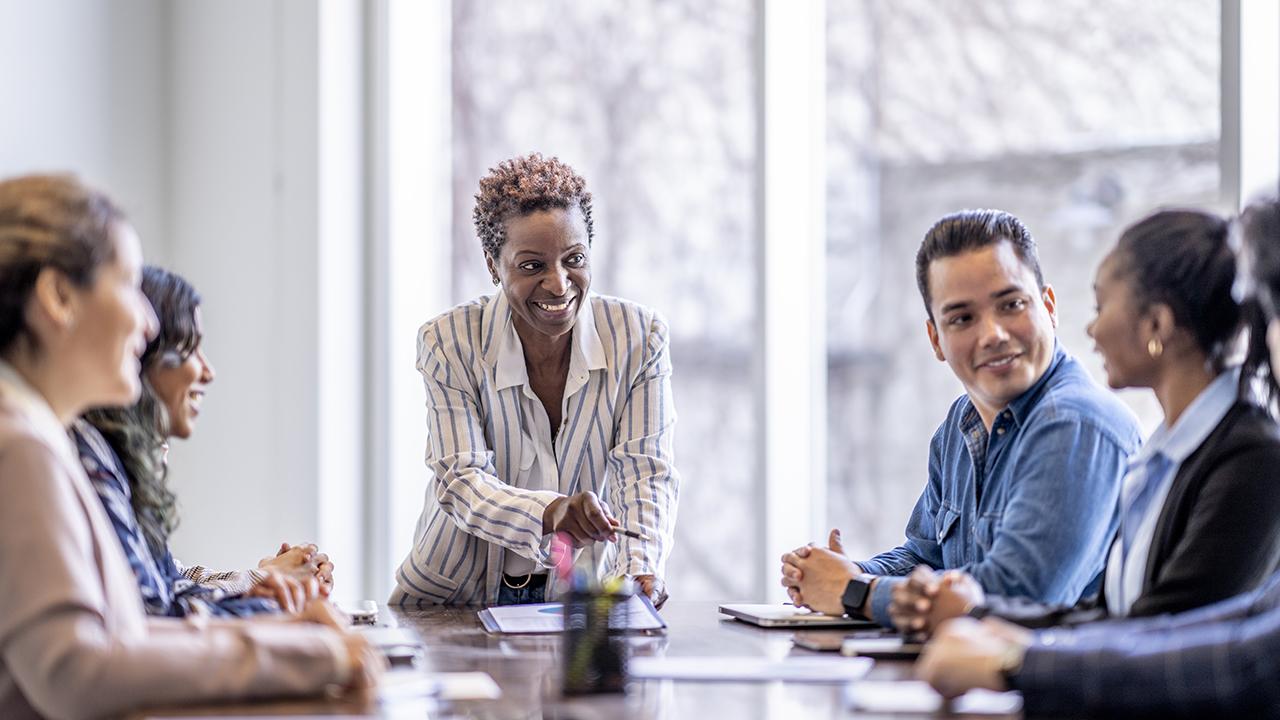 A small group of business professionals sit around a table as they meet to brainstorm some ideas.