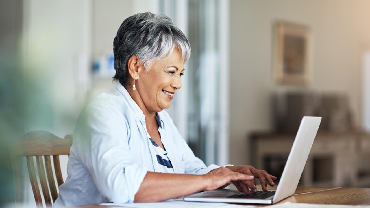 adult senior smiling while on computer
