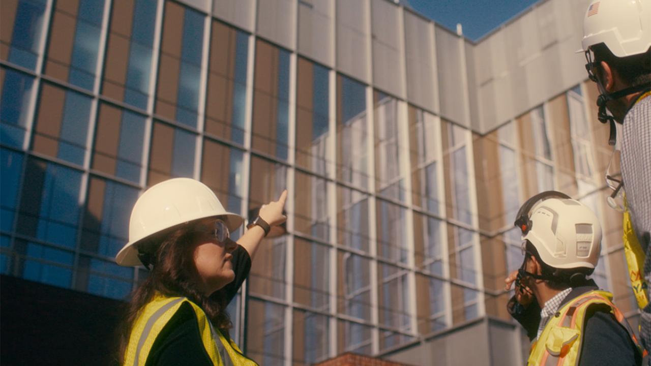construction professionals outside pointing and looking up at a building