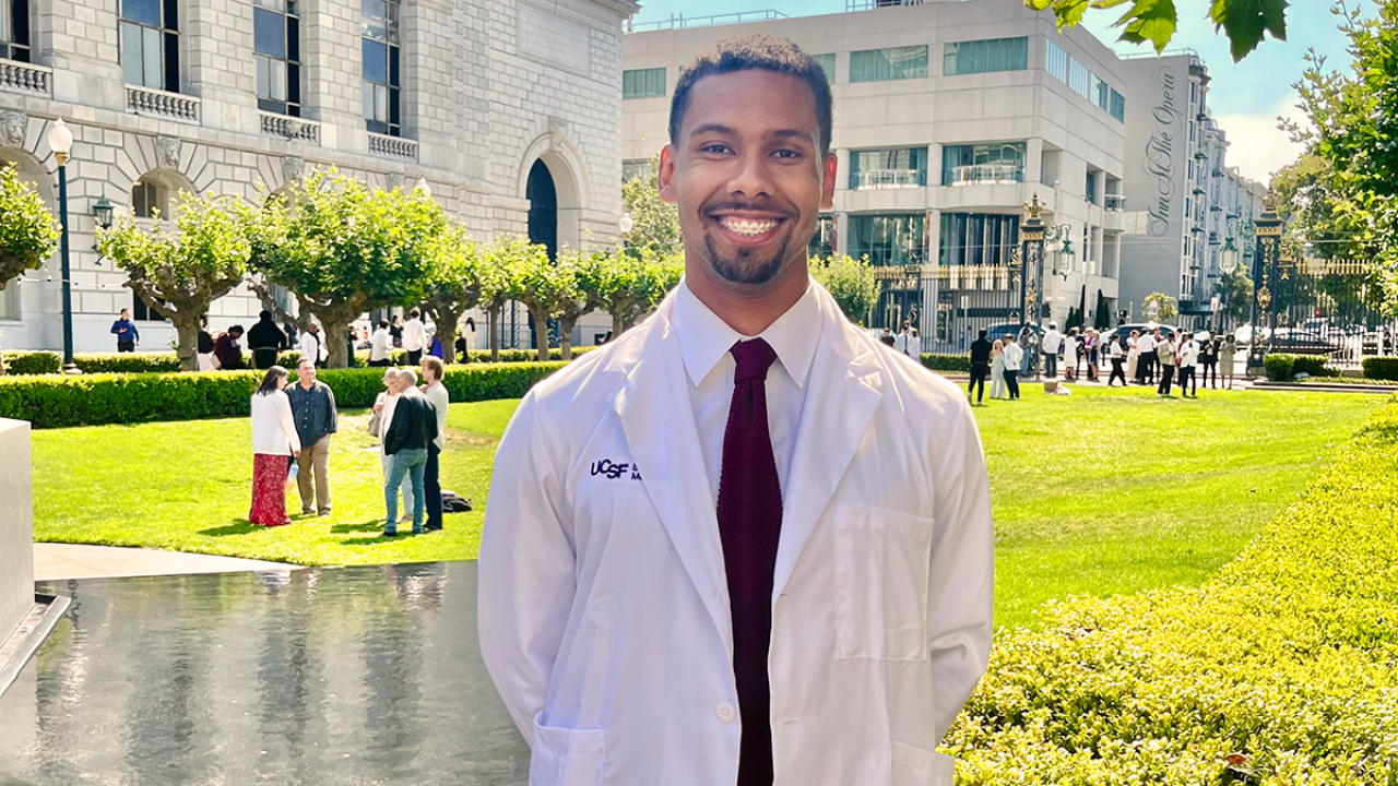 UC Davis Health Professions Post Bac grad Adejia Boutte poses in his white coat during his white coat ceremony for UCSF