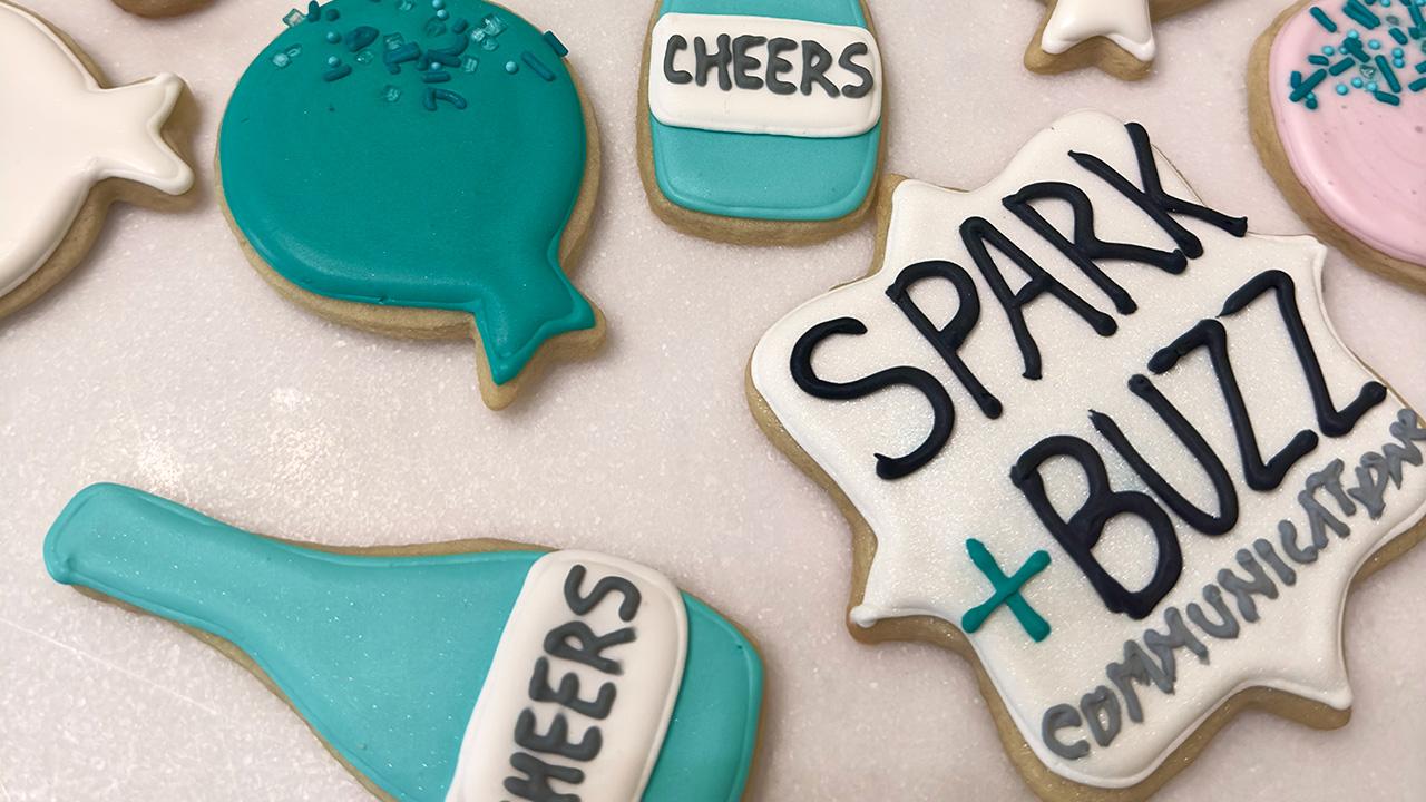 sugar cookies with the company name Spark + Buzz on them in icing