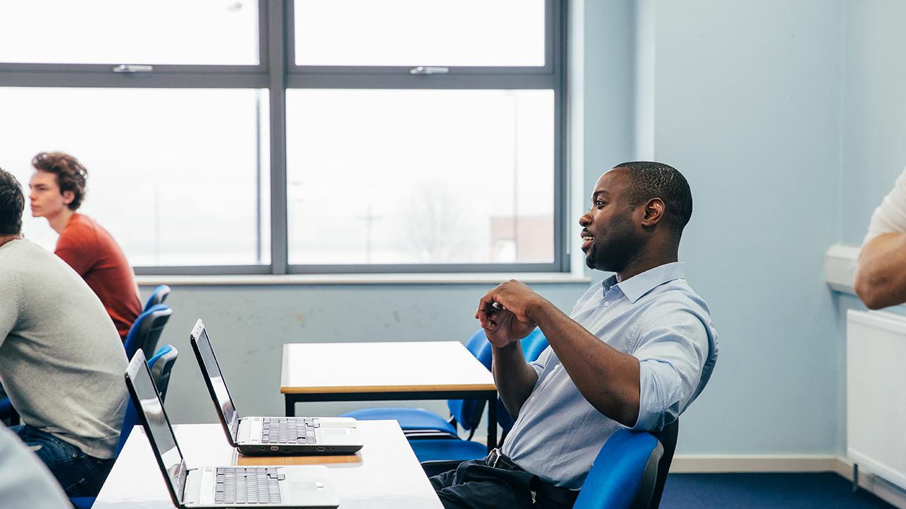 man sitting at desk listening to lecture in classroom