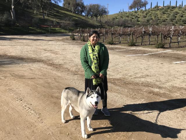 UC Davis Winemaking Certificate program grad Purnima Sreenivasan poses with her dog in a vineyard