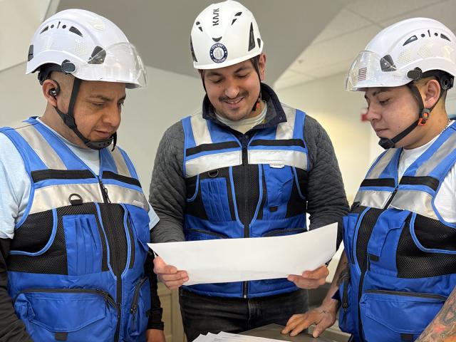 UC Davis CPE Construction Management Certificate Program grad Camilo Renteria, center, poses with his team while looking at construction plans