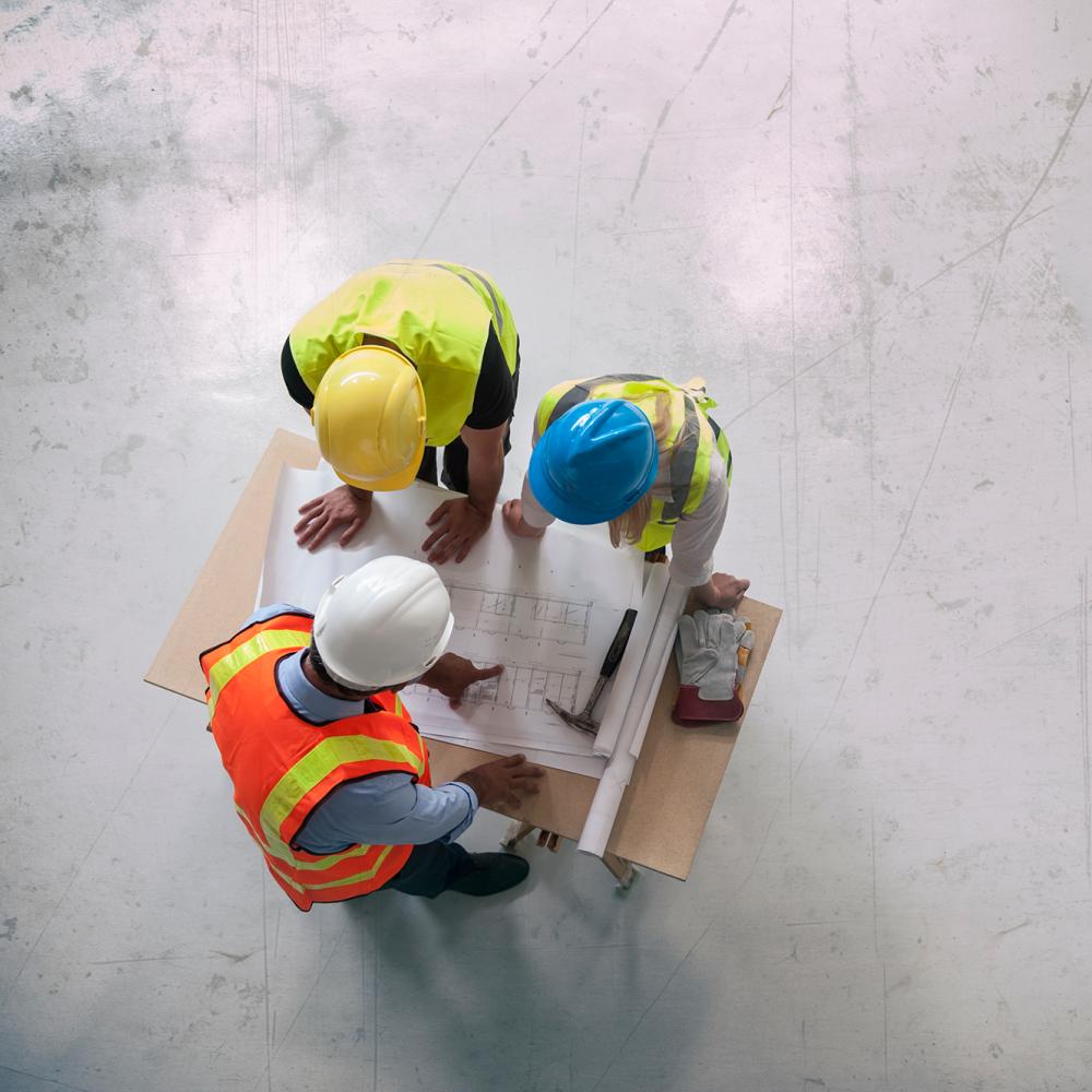 overhead shot of construction workers inspecting blueprints