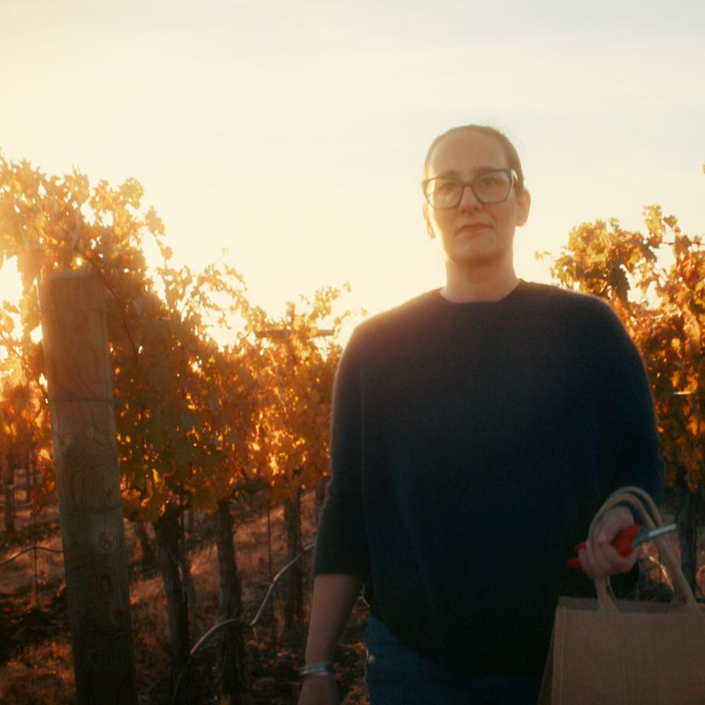 woman standing and smiling in a vineyard