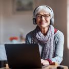 senior with headphones on at computer smiling