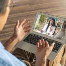 Man speaking to a woman via videoconference on a laptop.