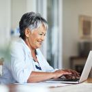 adult senior smiling while on computer