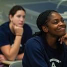 students sit at desks smiling