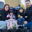A family with two parents and two young children in a stroller.