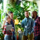 Four colleagues speak to each other in an office setting.