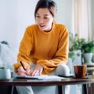 a woman holding a pen and signing paperwork in the living room at home