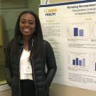 UC Davis health professions post-bac grad Kayla Hall posing next to her research project poster