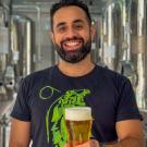 Michael and Sheila Lewis Brewing Scholarship winner Matheus Ramos poses with a glass of beer in a brewery