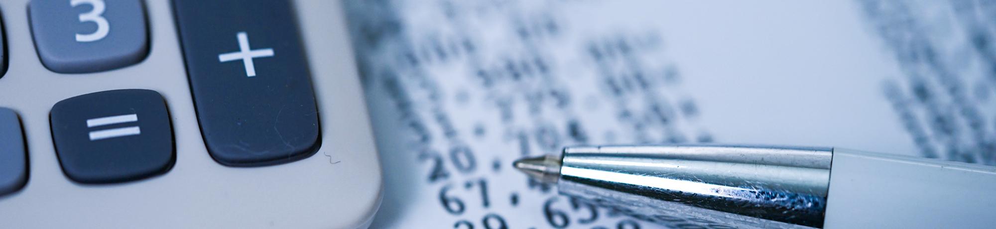 close up of calculator, pen and accounting spreadsheet