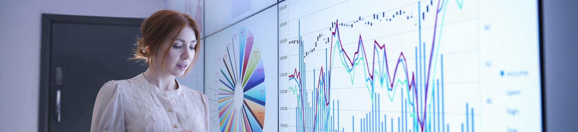 Woman analyzing data on big screens