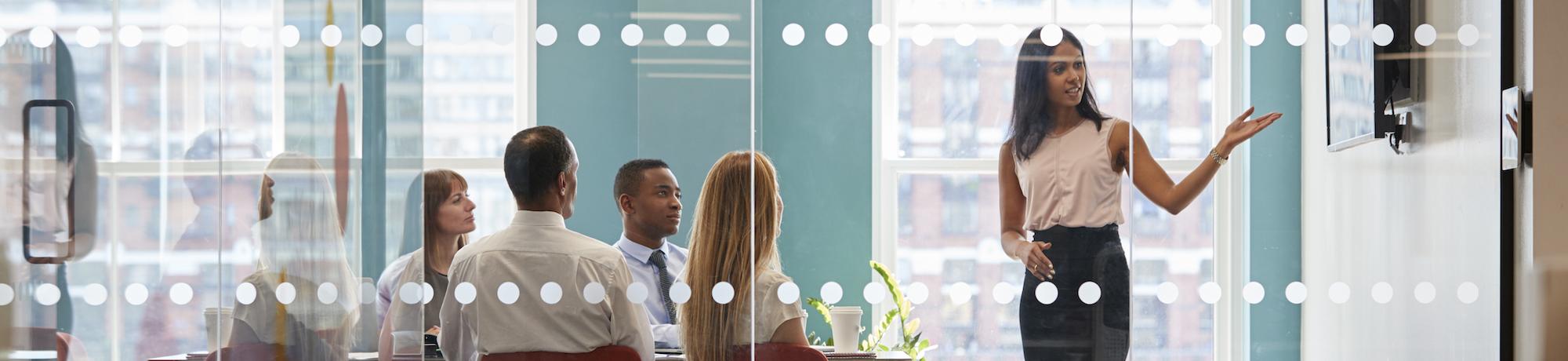 woman pointing at whiteboard in conference room during meeting